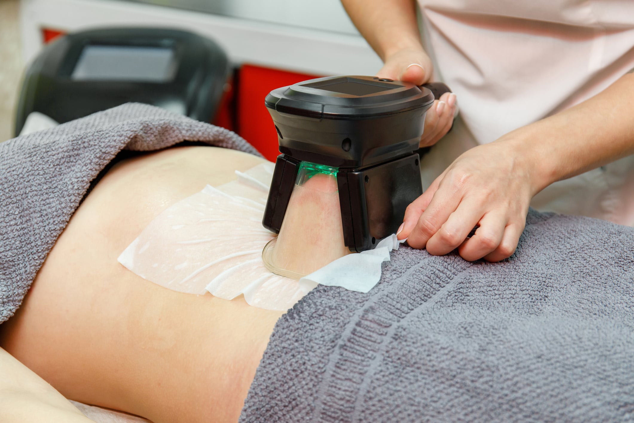 Beauty therapist applying cryolipolysis treatment. Non-surgical fat reduction and body sculpting in cosmetic cabinet